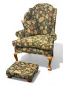WING-BACK ARMCHAIR & MATCHING FOOTSTOOL, green floral fabric upholstery, 117 (h) x 88 (w) x 85cms (