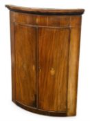 GEORGE III MAHOGANY BOWFRONT TWO-DOOR CORNER CUPBOARD, moulded cornice over a frieze with shell