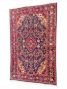HAMADAN WOOLLEN RUG, late 20th century, blue field centred with a red medallion, 190 x 113cms