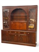 LARGE MAHOGANY-EFFECT WALL UNIT, illuminated upper section with an open shelf, over drinks cupboard,