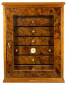 CONTEMPORARY BURR WALNUT CIGAR HUMIDOR, glazed single door enclosing seven drawers with brass knob