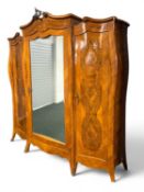 ITALIAN BURR WALNUT TRIPLE WARDROBE of bombé form, central mirrored door enclosing hanging space,