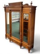 CONTINENTAL OAK TRIPLE BREAKFRONT WARDROBE having carved detail, three mirrored doors with