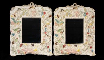 PAIR OF SPELTER FRAMED WALL MIRRORS, colourful painted repoussé decoration of cherubs, 29.5 x