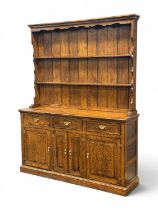 SOLID OAK WELSH DRESSER, in the 18th century style, with boarded plate rack, enclosed base with