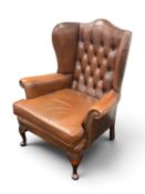 BROWN LEATHER-EFFECT WING-BACK ARMCHAIR with button back, cabriole frontal supports, 100 (h) x 90 (