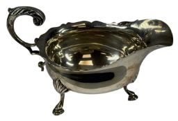VICTORIAN SILVER SAUCE BOAT with shaped rim, acanthus-capped scroll handle, on three hoof feet,