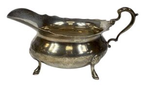 EDWARDIAN SILVER SAUCEBOAT with wavy rim, shaped handle, on three hoof feet, William Aitken,