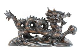 Drachenfigur China 20. Jh., Holz dunkel gebeizt u. geschnitzt, in der re. vorderen Klaue eine