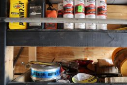 Contents of two shelves including grease, construction marker, oils, and tape, everything pictured