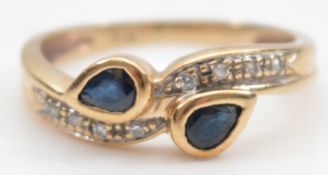 An unmarked 9ct gold sapphire and single cut diamond cross over ring, hallmarks missing due to