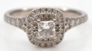 An 18ct white gold diamond cluster ring, claw set with a Princess cut stone weighing approximately