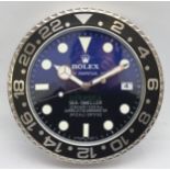 A 'Rolex' style advertising metal wall clock, blue and black gradient dial with black bezel, bearing
