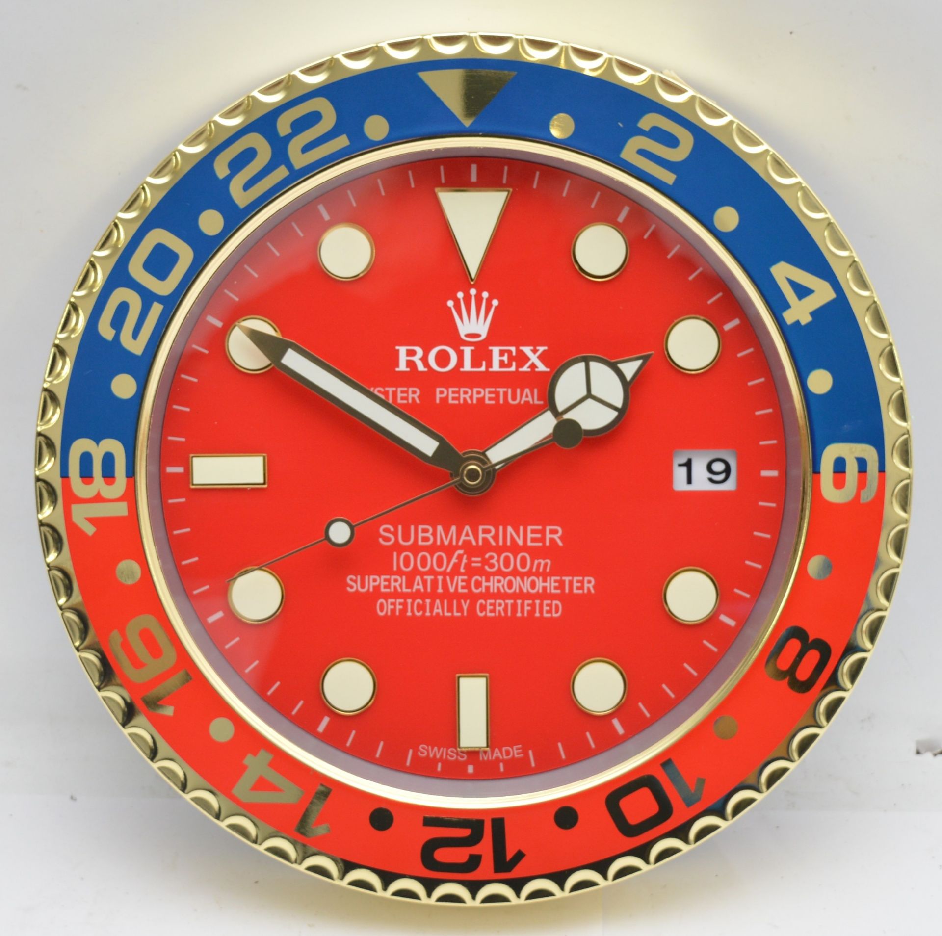 A 'Rolex' style advertising metal wall clock, red dial with blue and red bezel, bearing 'Rolex