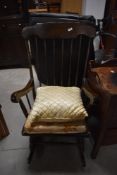 A traditional dark stained rocking chair , having turned frame