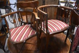Two Edwardian mahogany salon armchairs of similar design with matching features and upholstery