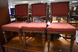 A set of three Victorian oak dining chairs having overstuffed seats and backs