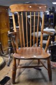 A 19th Century stained frame kitchen armchair having turned leg and H stretcher, worn to feet