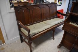 A George III oak settle having four fielded panes and cabriole style front legs