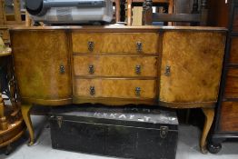 An early to mid 20th Century walnut sideboard having central drawers flanked by cupboards, on