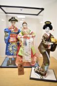 A group of three Korean costume dolls, two inside a plastic display cabinet.