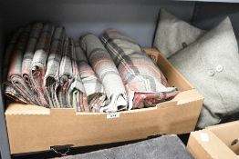 A carton of Wool tartan fabric having a moss green background and bands of brown, red and cream.