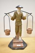 A large Oriental design resin figure depicting a water carrier, measures 43cm tall.