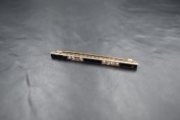 An Art Deco yellow metal diamond and onyx bar brooch having five alternate rows of four step cut