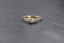 An 18ct gold diamond solitaire ring the small illusion set diamond within high moulded shoulders