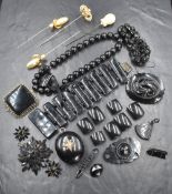 A lined tin box containing a small selection of black mourning jewellery including a locket,