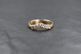 A 9ct gold cubic zirconia set wishbone ring, the seven round cut cubic zirconia in a wishbone