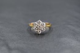 An 18ct gold daisy cluster ring having seven brilliant cut diamonds totalling approx 1ct in a claw