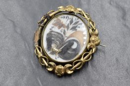 A large yellow metal mourning hair brooch, the central panel having decorative hair scrolls in an