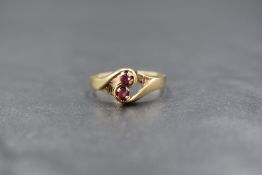A 9ct gold ruby duo ring having two small claw set rubies in a crossover mount on a 9ct gold loop,