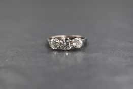 An 18ct white gold and platinum three stone diamond set ring, the graduated round brilliant cut