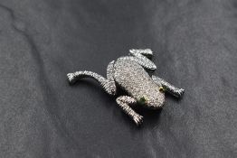 A white metal diamond encrusted articulated frog brooch stamped 750, the frog having approx 120 pave