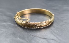 A 9ct gold hinged bangle, the bangle having decorative scroll engraving with twisted rope motif