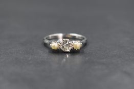 An 18ct white gold pearl and diamond set trilogy ring, the central old cut diamond measuring