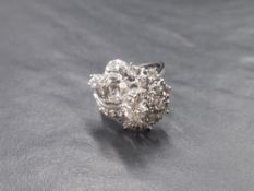 A white metal multi cluster stylised diamond ring stamped 750, the central raised diamond being