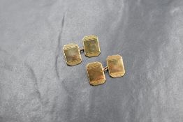 A cased pair of 9ct gold cufflinks having canted rectangular panels with cut decoration and chain