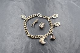 A white metal curb link bracelet stamped sterling having seven assorted charms, 2 being loose