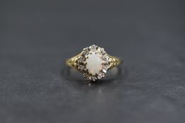 A 9ct gold opal and diamond cluster ring having a central oval opal cabochon within an illusion