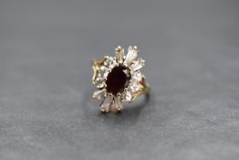 A 9ct gold paste set cluster ring, the central oval cut red paste in a twelve cubic zirconia