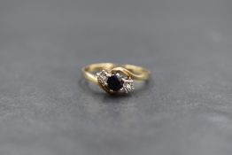 A 9ct gold sapphire and diamond three stone ring, the central round cut sapphire flanked by two