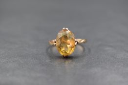 A 9ct rose gold citrine ring having an oval citrine in a claw set collared mount on a rose gold loop