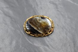 A large oval brown striped agate brooch in a decorative pinchbeck mount