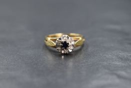 An 18ct gold sapphire and diamond chip cluster ring having a small central sapphire within a diamond