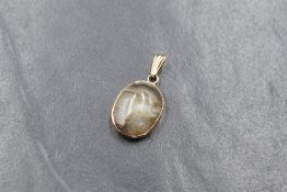 A yellow metal presumed gold agate set pendant, the oval agate cabochon in a bezel setting,