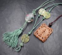 A Chinese carved orange jade style pendant depicting two fish within water, with a wooden bead on