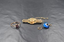 A small yellow metal bar brooch stamped 9ct having central seed pearl and ruby decoration and